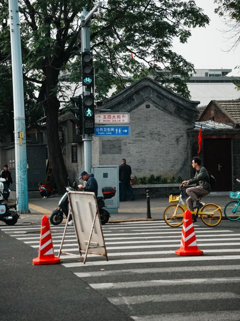 Urban street scene in Beijing featuring bicycles, pedestrians, and traffic cones, Huizhou, Guangdong