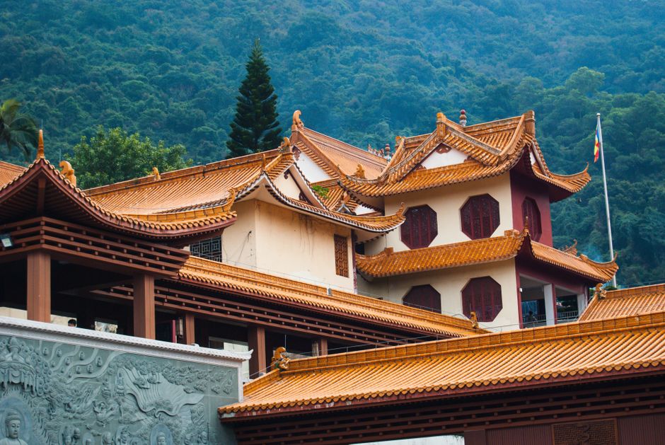 Serene traditional Chinese temple with ornate roofs against lush mountainous backdrop, Huizhou, Guangdong