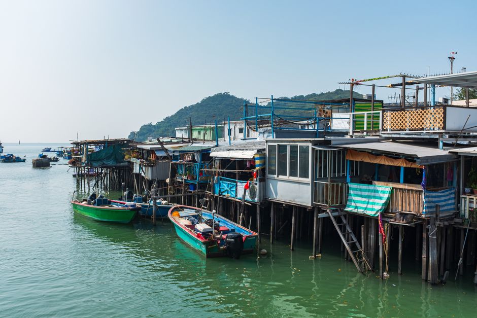 Scenic view of stilt houses along waterfront in New Territories, Hong Kong, with moored colorful boats, Huizhou,...