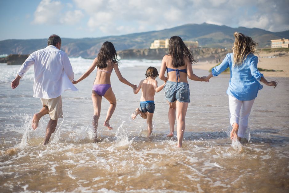 A family having fun running into the ocean on a sunny beach day in Portugal. Joyful and carefree moments, Huizhou,...