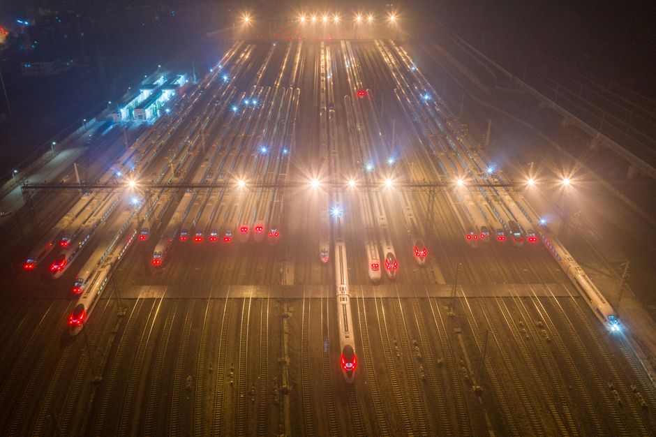 A nighttime aerial view of trains at an illuminated railway station in Nanjing, China.
