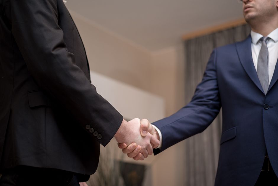 Two businessmen in suits shaking hands, emphasizing trust and partnership indoors, Huizhou, Guangdong
