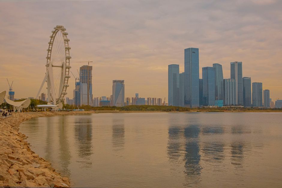 Captivating view of Shenzhen skyline and Ferris wheel reflected in the water during twilight. — Huizhou, Guangdong, China