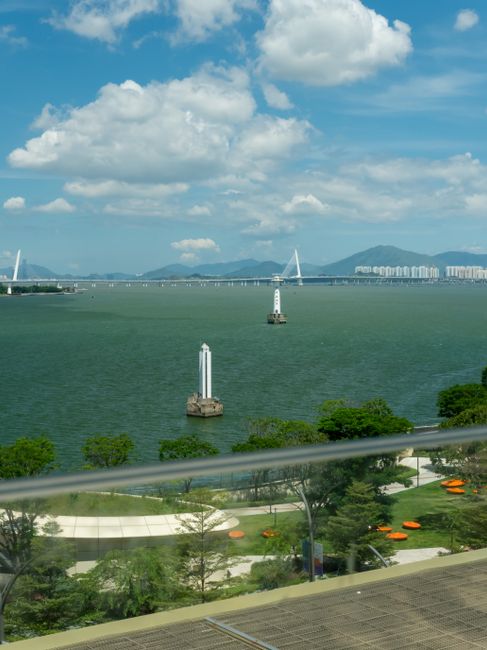 Beautiful view of Shenzhen Bay featuring distinctive lighthouses and distant city skyline under a clear blue sky. —