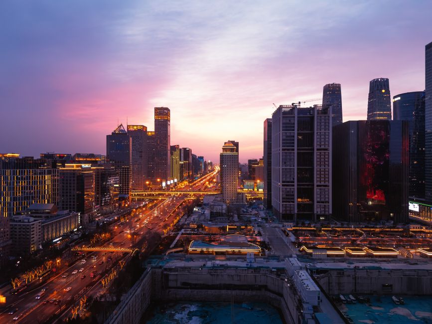 A breathtaking panoramic view of Beijing's urban skyline at dusk with vibrant city lights and a colorful sky. —