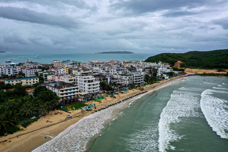Drone captures vibrant Sanya coastline with beachfront buildings and lush greenery. — Huizhou, Guangdong, China