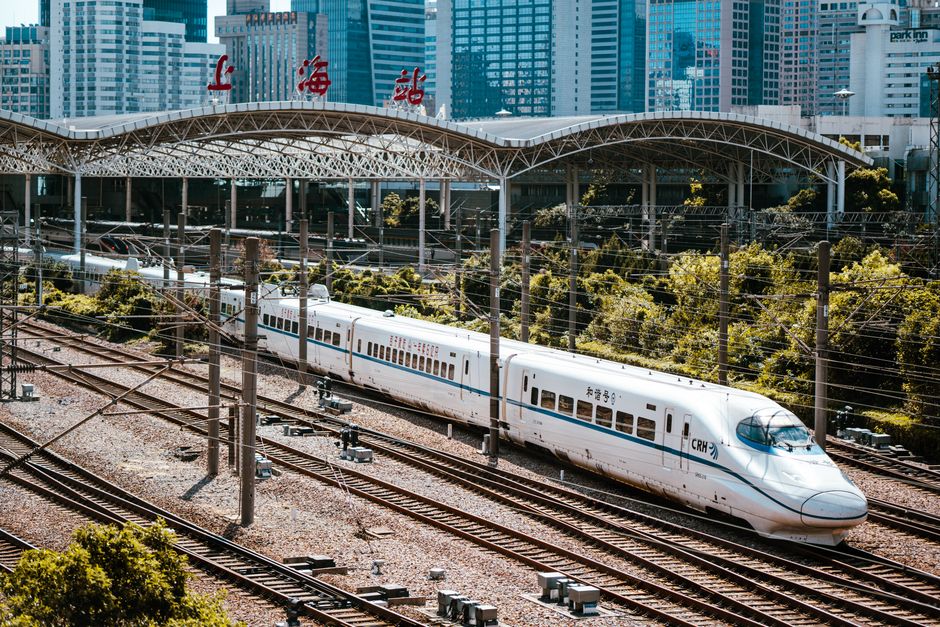 A high-speed train passing through Guangdong Railway Station with city skyline in the background.